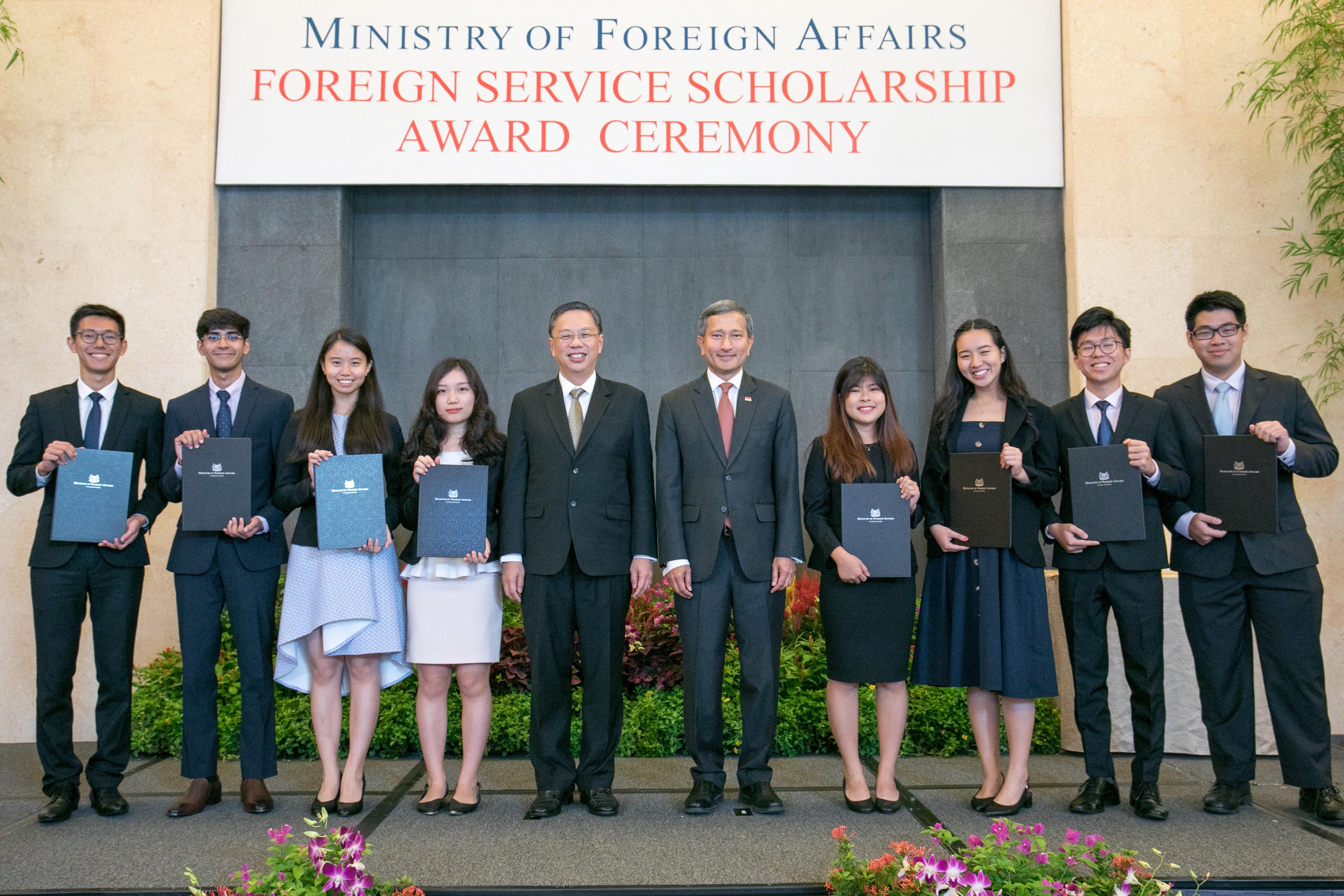Two men in suits shake hands before flags of Singapore, Austria, and the European Union.